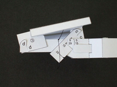 主翼固定部品(後)③と胴体⑥の切り込みdをかみ合わせる。仰角調整板④と胴体⑥の数字をかみ合わせる。 