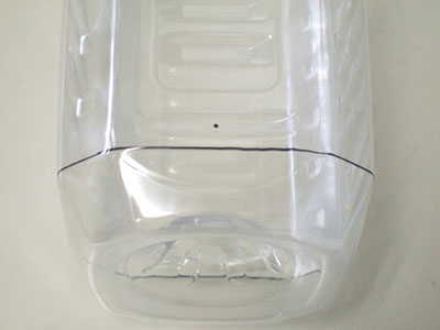 ペットボトル短辺の中央で、切り取り線から10～15mm程度離れた所に印をつけ、穴をあける。