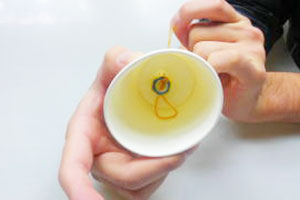 紙コップの内側から、そこの穴を通して、輪ゴムを引っ張り出します。